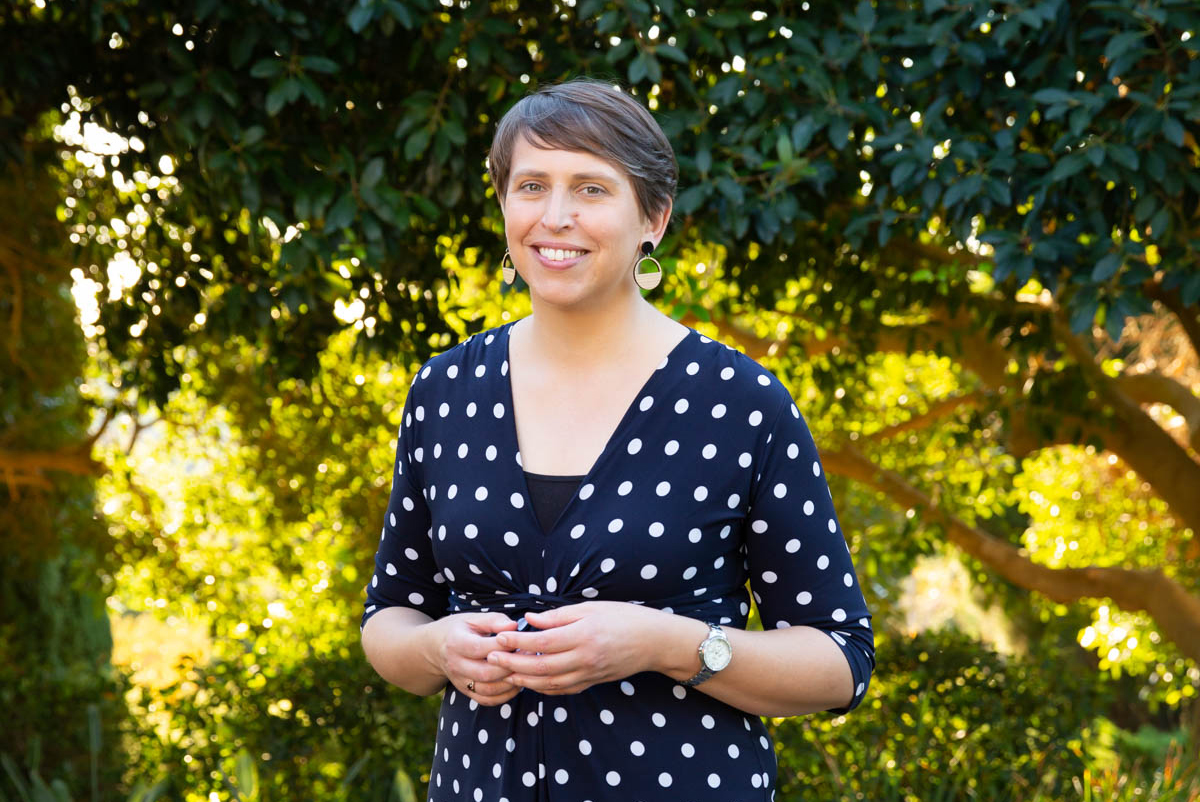 Rachel standing in front of foliage with a warm and friendly smile